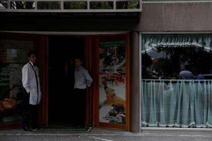 Trabajadores se paran en la puerta de un restaurante durante un apagón en Caracas, Venezuela.