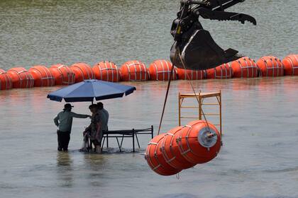 Trabajadores toman un descanso mientras colocan las boyas en el río Bravo, el miércoles 12 de julio de 2023, a la altura de Eagle Pass, Texas (AP Foto/Eric Gay)