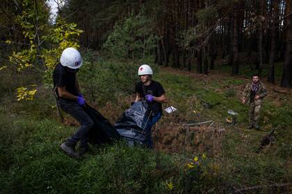 Trabajadores ucranianos remueven el cuerpo de un soldado ruso muerto en Lyman