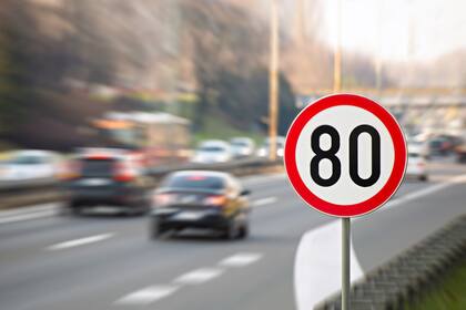 Traffic sign showing 80 km/h speed limit on a highway full of cars