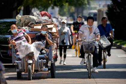 Transeúntes con mascarillas en las calles de Pekín. (AP Photo/Mark Schiefelbein)
