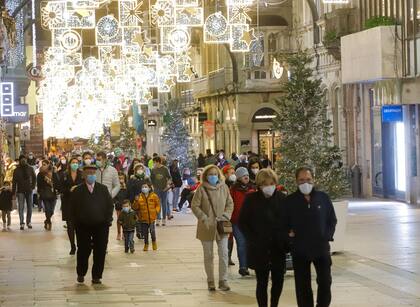 Transeúntes pasean bajo las luces navideñas, llevando mascarilla, en Vigo, Galicia (España) - Europa Press