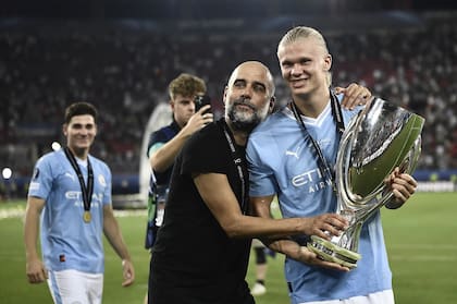 Tras el título de Manchester City en la Supercopa de Europa, Pep Guardiola festeja con Erling Haaland y el trofeo; detrás, sonríe Julián Álvarez.