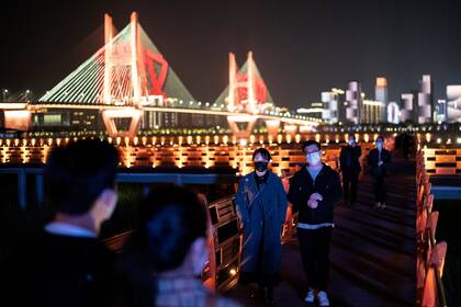 Tras levantarse la cuarentena, la gente pasea en el parque junto al río Yangtze, en Wuhan, en la provincia central china de Hubei; el uso de barbijos sigue siendo una costumbre tras la pandemia de coronavirus
