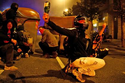 Jóvenes con la cara cubierta y cascos de moto levantaron barricadas a base de contenedores de basura y cartones, a los que prendieron fuego.