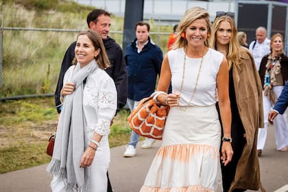 Tras unos días juntas en Grecia, Máxima invitó a Florencia Di Cocco (a la izquierda) y a su pareja, Pablo Tomé, a disfrutar de la carrera. Su amiga es argentina; eran compañeras del colegio Northlands. Su Majestad apostó a un look fresco, con top y falda de la marca griega Zeus & Dione y cartera de Marina Raphael