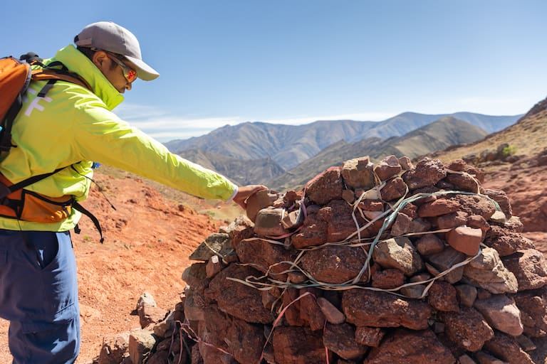 El carguero acompaña con una mula de apoyo y burros que trasladan el equipaje. Ofrendas en una apacheta del camino. (Fotos: Belén Grosso)