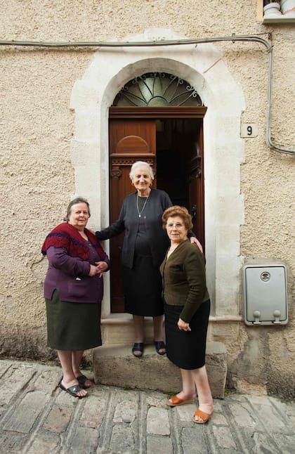 Tres amigas posan para la foto en la puerta de una casa de Prizzi.