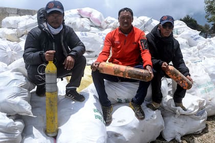 Tres guías de montaña posan con tubos de oxígeno recuperados camino a la cumbre del Everest