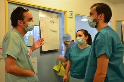Tres médicos dialogan en el hospital Bichat de París con los barbijos de rigor por el coronavirus