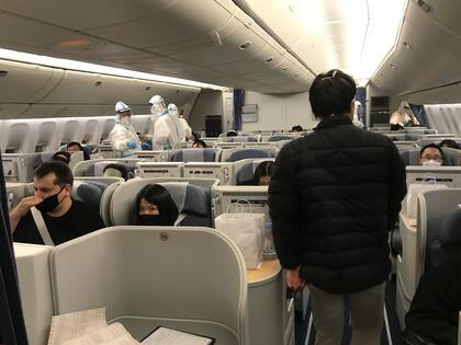 Tripulantes de cabina con equipos de protección observan a los viajeros que se dirigen a China embarcar en un vuelo que sale del aeropuerto JFK de Nueva York el 24 de diciembre de 2022. 