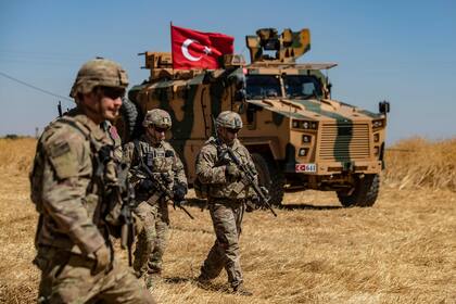 Tropas estadounidenses pasan junto a un vehículo militar turco durante una patrulla conjunta con tropas turcas en la aldea siria de al-Hashisha