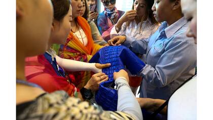 Turistas chinos tocan una piel de cocodrilo teñida en la granja de Sriracha
