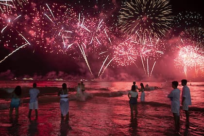 Turistas disfrutan de los fuegos artificiales en la playa: una clásica postal de Año Nuevo en Río de Janeiro.