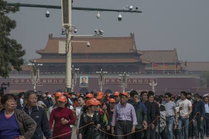 Turistas haciendo fila para visitar el mausoleo de Mao en Pekín, debajo de un poste que sostiene once cámaras de vigilancia