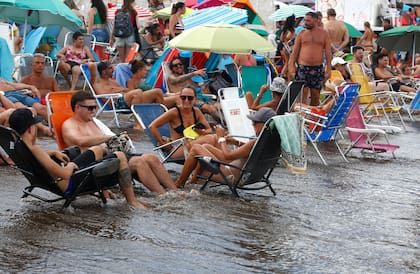 Turistas instalados en la orilla como para que la rompiente los refresque