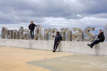 Turistas posando para la foto en el cartel de Punta Arenas frente al mar