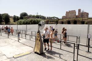 Turistas se refrescan con un ventilador en la cola para visitar el Coliseo de Roma