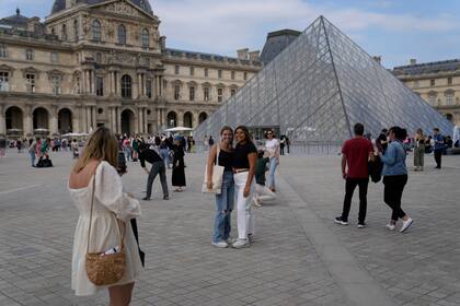 Turistas se sacan fotos frente a la Pirámide del Museo del Louvre, en París