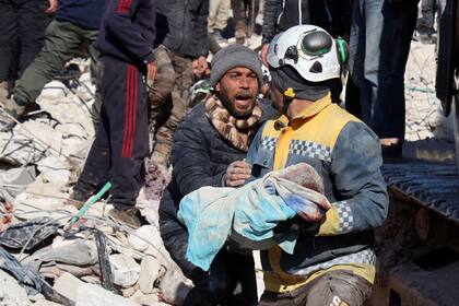 TOPSHOT - Un hombre reacciona cuando el cuerpo de su bebé sacado de entre los escombros, es llevado por un rescatista sirio de los Cascos Blancos, en la ciudad de Harim en la provincia noroccidental de Idlib en Siria, controlada por los rebeldes, en la frontera con Turquía, el 8 de febrero. , 2023, dos días después de un terremoto mortal que azotó a Turquía y Siria.  (Foto de Mohamed AL-RIFAI / AFP)