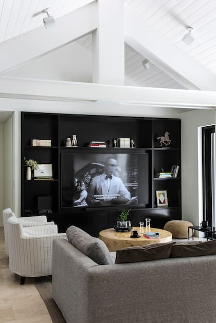 TV integrada a una biblioteca negra y mesa ratona de raíz de piopo ‘Balzac’ (Duveen).