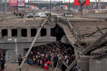 Ucranianos se concentran debajo de un puente destruido mientras intentan cruzar el río Irpin en las afueras de Kiev, Ucrania, el 8 de marzo de 2022