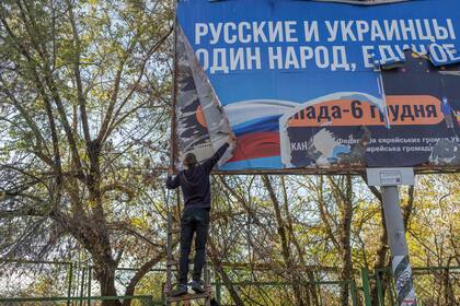 Un adolescente retira una pancarta rusa en la que se lee "Rusos y ucranianos son un solo pueblo" en la recién liberada Kherson el 14 de noviembre de 2022, en medio de la invasión rusa de Ucrania.