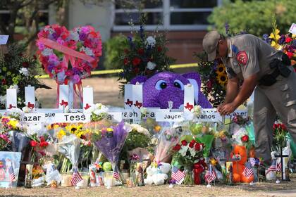 Un agente de la Patrulla de Carreteras de Texas coloca un artículo en un monumento para las víctimas del tiroteo masivo del martes en la Escuela Primaria Robb el 27 de mayo de 2022 en Uvalde, Texas. 