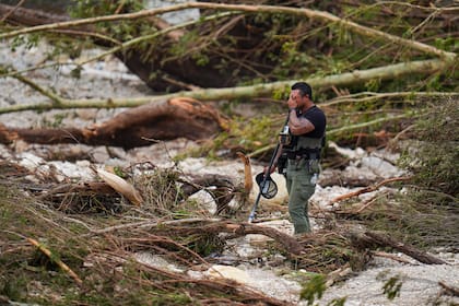 Un agente de la policía del condado hace una pausa mientras busca en las orillas del río Guadalupe cerca de Camp Mystic, tras una inundación repentina en la zona, el sábado 5 de julio de 2025, en Hunt, Texas. (AP Foto/Julio Cortez)