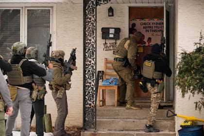 Un agente federal de inmigración utiliza un ariete para derribar una puerta antes de realizar un arresto, el domingo 11 de enero de 2026, en Minneapolis