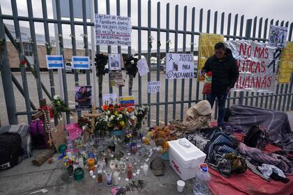 Un altar con velas y fotos cubre la cerca afuera del centro de detención de migrantes que fue el sitio de un incendio mortal, mientras los migrantes se despiertan después de pasar la noche en la acera en Ciudad Juárez, México, el jueves 30 de marzo de 2023. 