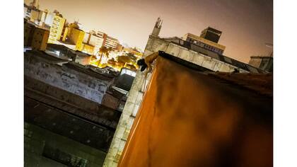 Un "pichador", un artista de graffiti que marca edificios y monumentos con fuentes angulares y rúnicas, pinta su firma personal, llamada "pichacao", encima de un edificio de apartamentos, en San Pablo