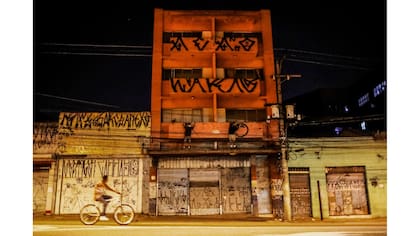 Un ciclista pasa junto a "pichadores", pintan la fachada de un edificio en San Pablo, Brasil
