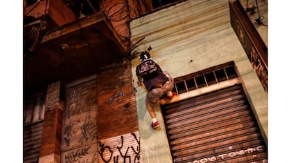 Un "pichador" escala una casa antes de pintar su firma personal, llamada "pichacao", en la fachada