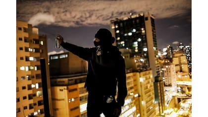 Un "pichador", un artista de graffiti que marca edificios y monumentos con fuentes angulares y rúnicas, posa en la terraza de un edificio