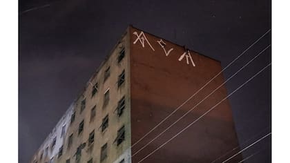 Un "pichador", un artista de graffiti que marca edificios y monumentos con fuentes angulares y rúnicas, pinta su firma personal, llamada "pichacao", encima de un edificio de apartamentos, en San Pablo