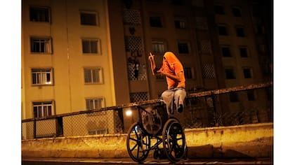 Un "pichador" que perdió las piernas después de sufrir un accidente mientras saltaba trenes, posa para una fotografía en una calle después de pintar una pared con su firma personal