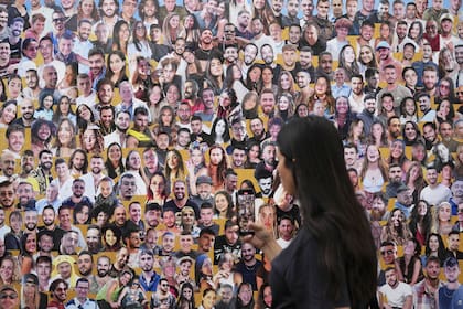 Un asistente camina a través de un mural con retratos de las víctimas en el lugar del festival de música Nova, donde cientos de asistentes fueron asesinados y secuestrados por Hamas y llevados a Gaza, en el primer aniversario del ataque, cerca del Kibbutz Reim, en el sur de Israel, el lunes 7 de octubre de 2024. (Foto AP/Ariel Schalit)