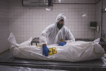 Un asistente de la morgue en la sucursal de Pretoria de la empresa sudafricana de servicios funerarios y de entierro Avbob aplica una advertencia de riesgo biológico en el cuerpo de un paciente fallecido por enfermedades relacionadas con Covid-19 el 22 de enero de 2021