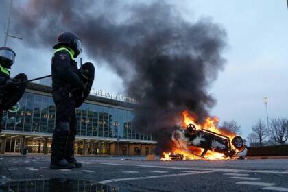Un automóvil fue incendiado frente a la estación en la plaza 18 de septiembre en Eindhoven, Países Bajos, 24 de enero de 202. Esto ocurrió durante las protestas contra el toque de queda