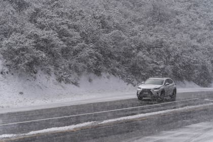 Un automovilista conduce sobre una carretera nevada en el Bosque Nacional Angeles cerca de La Canada Flintridge, California