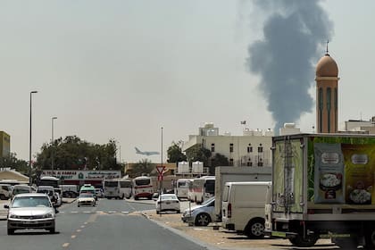 Un avión de Emirates aterriza mientras una columna de humo se eleva por un incendio en curso en el Aeropuerto Internacional de Dubai