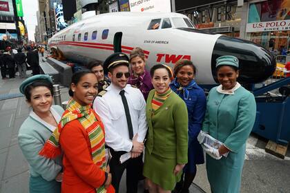 Varios actores vestidos como empleados de TWA, posan para un fotos con el avión L-1649A
