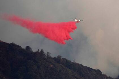 Un avión lanza retardante sobre los incendios cerca del observatorio Mount Wilson, en California
