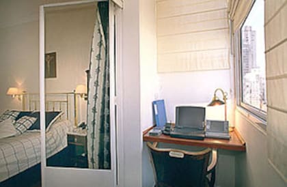 Un balcón cerrado se aprovecha como miniestudio con un escritorio hecho con una plancha de madera amurada a lo ancho del espacio