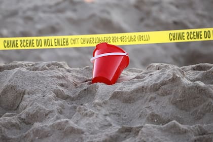 Un balde junto a una cinta de precaución en la playa en Lauderdale-by-the-Sea donde ocurrió la tragedia