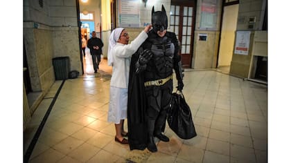 La hermana Adriana ayuda a Batman con su capa antes de visitar a los niños
