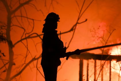 Un bombero entre las llamas que rodean a la ciudad costera de Malibú