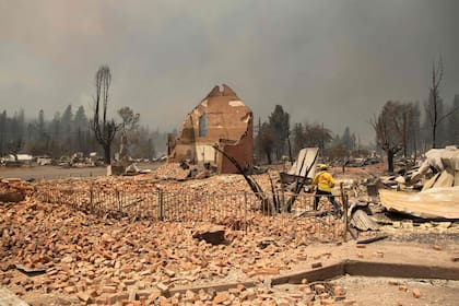 Un bombero inspecciona un edificio histórico que se quemó durante el incendio de Dixie en el centro diezmado de Greenville, California.
Greenville, es un asentamiento de Indian Valley de unos pocos cientos de personas que se remonta a la Fiebre del Oro de mediados del siglo XIX. Fue envuelto por las llamas cuando los vientos dirigieron el infierno hacia la comunidad, volviendo el cielo naranja