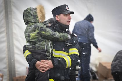 Un bombero rumano lleva a un niño refugiado procedente de Ucrania en la frontera entre Ucrania y Rumania en Siret el 2 de marzo de 2022